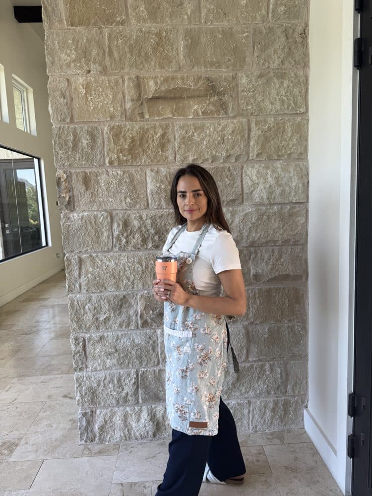 Betty standing against a plain wall in her apron outfit, raw phone photo.